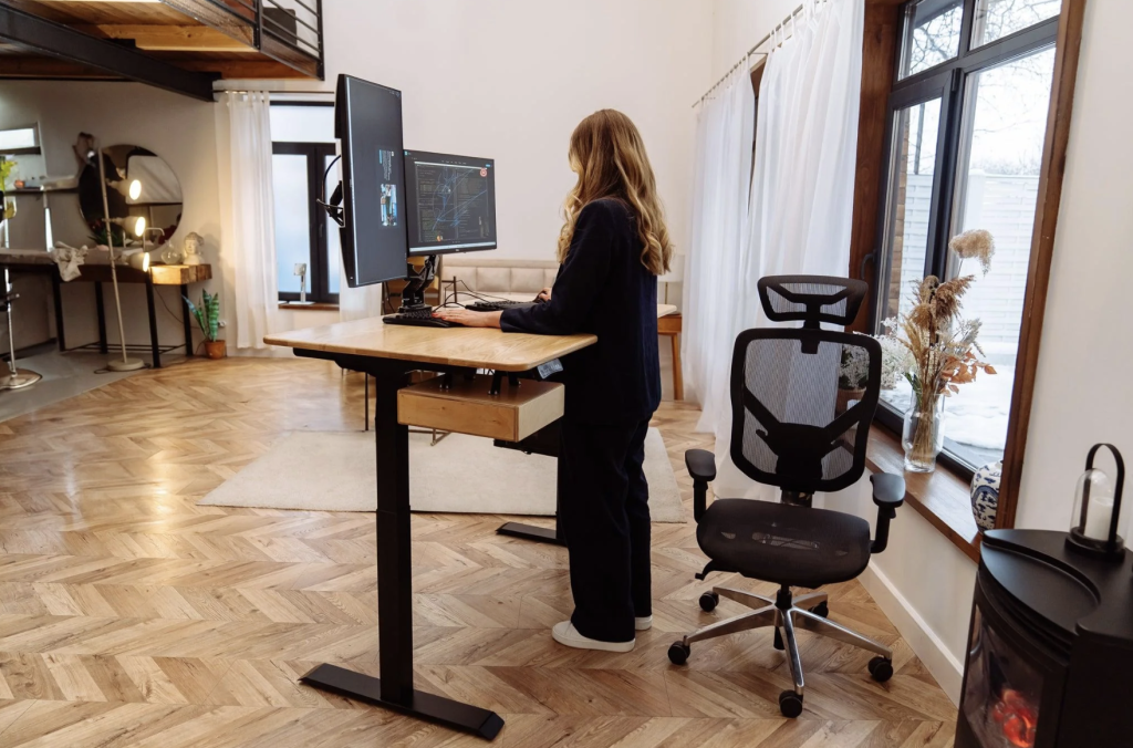 Un laptop așezat pe un suport la nivelul ochilor, cu o tastatură externă în față.