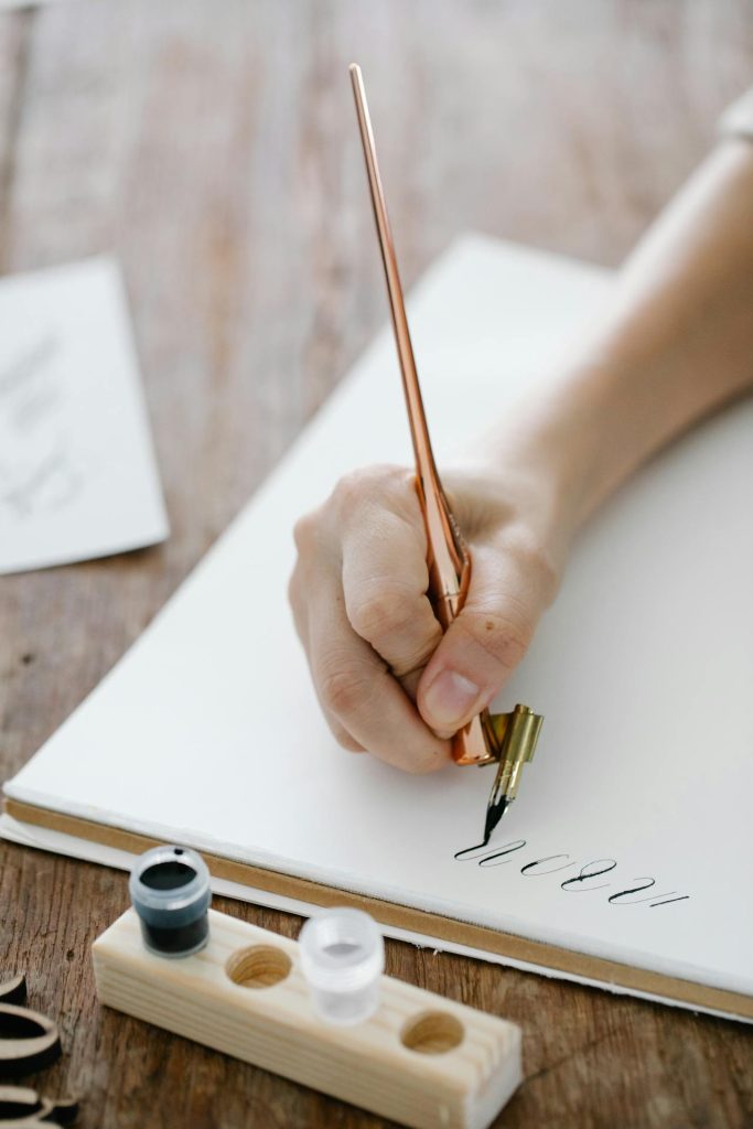 Изображение: Лист бумаги с линовкой для каллиграфии (базовые линии, линии высоты строки, выноса), на котором написаны тренировочные буквы.